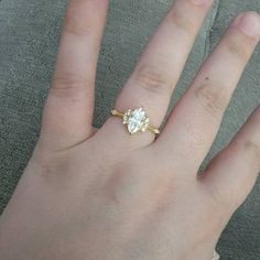 a person's hand with a gold ring on top of it and a diamond in the middle