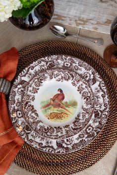 a plate with a bird on it sitting on top of a table next to silverware