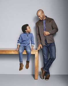 a man standing next to a little boy sitting on a table