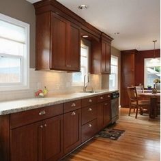 a large kitchen with wooden cabinets and white counter tops, along with a dining room table