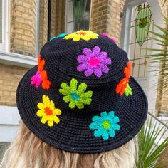 a woman wearing a black crocheted hat with colorful flowers on it