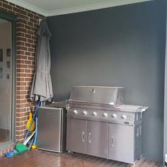 an outdoor kitchen with stainless steel appliances and hard wood flooring in front of a brick wall