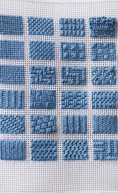 knitted squares are arranged in rows on a white surface with blue thread and stitching