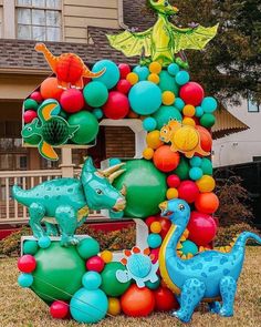 an inflatable number one with balloons and dinosaurs on it is sitting in front of a house