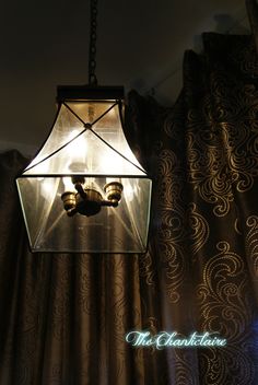 a lamp hanging from the ceiling in front of curtains