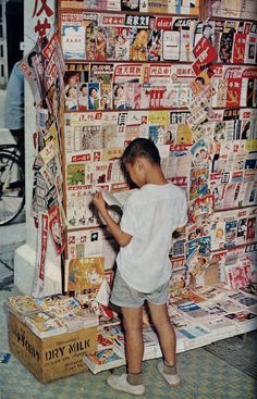 a young boy standing in front of a display of magazines