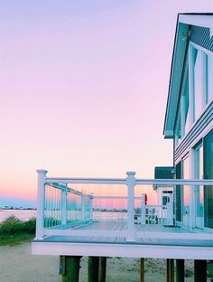 a white house sitting on top of a sandy beach next to the ocean at sunset