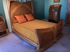 a wooden bed sitting next to a dresser and chair in a room with blue walls