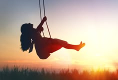 a girl swinging on a swing at sunset