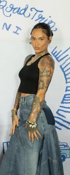 a woman with tattoos standing in front of a wall