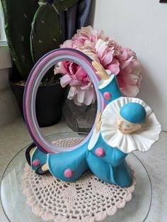 there is a glass plate with a blue horse on it and pink flowers in the background