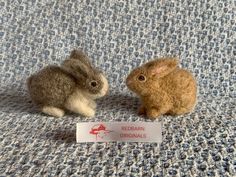 two small stuffed animals sitting next to each other on a blue cloth covered bed sheet