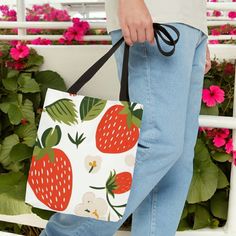 a person carrying a bag with strawberries on it and pink flowers in the background