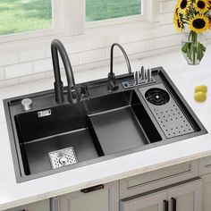 a kitchen sink sitting on top of a counter next to a vase with flowers in it