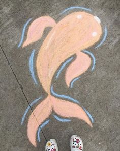 someone's feet standing in front of a chalk drawing of a koi fish