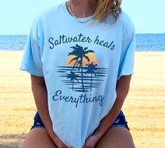 Saltwater Heals Everything Retro Tropical Sunset Tshirt, Vintage Beach Palm Tree Shirt .: 100% Airlume combed and ringspun cotton (fiber content may vary for different colors) .: Light fabric (4.2 oz/yd² (142 g/m .: Retail fit .: Tear away label .: Runs true to size PROPER SIZING Please see photos to see a specific sizing chart for this clothing style. These shirts are unisex size, meaning they are not women's fitted shirts. If would like a more fitted look, we suggest that you size down. To get your size, lay your favorite shirt at home flat, measure armpit to armpit, and then compare to the size chart in the photos. CARE INSTRUCTIONS Machine wash cold, inside-out, gentle cycle with mild detergent and similar colors. Use non-chlorine bleach, only when necessary. No fabric softeners. Tumbl Vacation T-shirt With Palm Tree Print And Relaxed Fit, Relaxed Fit T-shirt With Palm Tree Print For Vacation, Relaxed Fit Palm Tree Print T-shirt For Vacation, Palm Tree Shirt, Beachy Relaxed Fit Palm Tree Print T-shirt, Relaxed Fit Palm Tree Print T-shirt, Retro Tropical, Tropical Sunset, Fitted Shirts