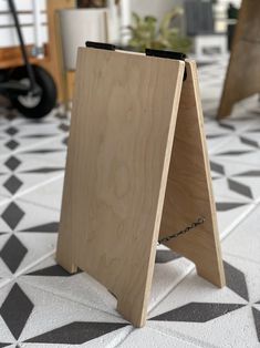 a wooden sign sitting on top of a white and black tile floor next to a potted plant