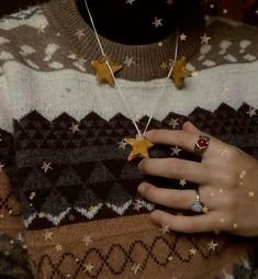 a person wearing rings and sweater with stars on them