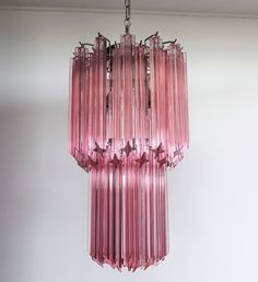 a pink chandelier hanging from the ceiling in a room with white walls and flooring