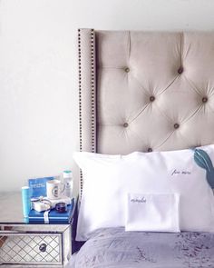 a bed with white sheets and pillows on top of it next to a night stand