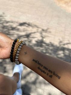 a person with a wrist tattoo that says and then you are living despite it all