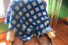 a blue and yellow blanket sitting on top of a brown chair