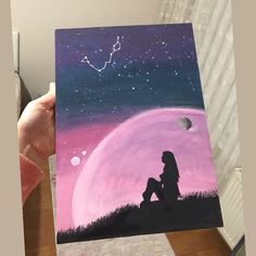 a person holding up a painting with the sky in the background and stars on it