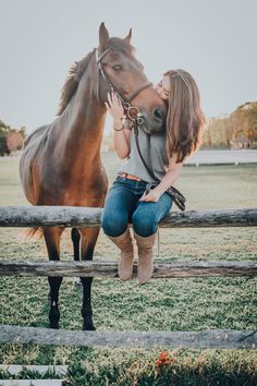 a woman kissing a horse in front of a fence