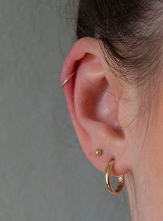 a close up of a person's ear with two small gold hoops on it