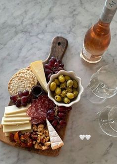 cheese, crackers, olives, nuts and wine on a marble table