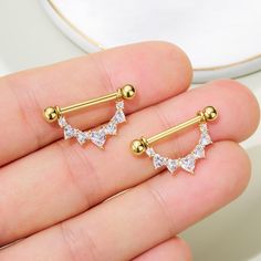 pair of gold nose piercings with crystal stones in the shape of triangle, on white background