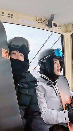 two snowboarders sitting in the back of a ski lift