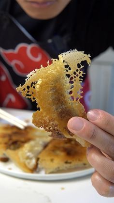 a person eating food on a plate with chopsticks