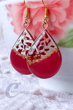 red and gold drop earrings on a lace tablecloth with pink flowers in the background