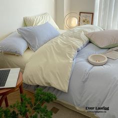 a laptop computer sitting on top of a bed next to pillows and pillowcases