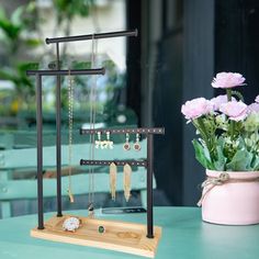 there is a vase with pink flowers and jewelry on display in front of the window