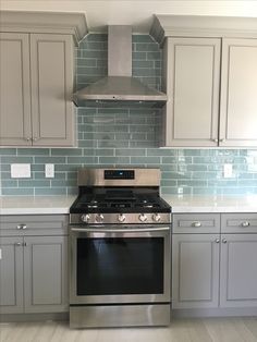 a stove top oven sitting inside of a kitchen next to white cupboards and drawers