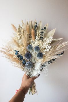 a hand holding a bouquet of dried flowers