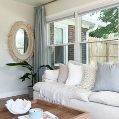 a living room filled with furniture and a large mirror on the wall above it's windows