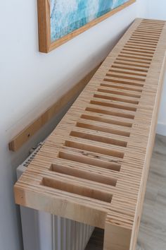 a wooden bench sitting in front of a painting on the wall next to a radiator