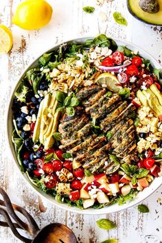 a salad with grilled meat, tomatoes, blueberries and other vegetables on it