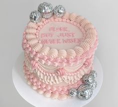 a pink and white cake with silver candies on the side that says, older but just never wiser