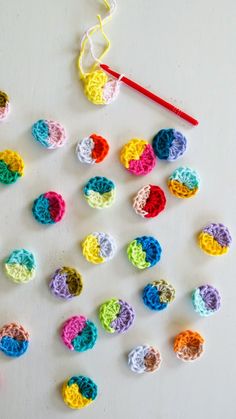 crocheted balls and yarn are arranged on a white surface with a knitting needle next to them