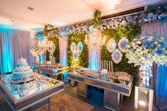 a wedding reception setup with blue lighting and white flowers on the wall, cake table