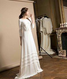 a woman standing in front of a mirror wearing a white dress