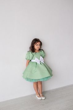 Sage Green Satin dress Girl Baby Ivory dress First Birthday outfit Sage Green Flower Girl Dress Princess dress Toddler party dress Fancy dress girl Satin dress with pearls on the sleeves If your little girl is having a birthday or invited to a party, this sage green satin dress with puffy sleeves is simply essential. With this special occasion dress girls will be little fairies at any wedding, anniversary or birthday event. The satin dress special design has been created for making your girl loo Spring Baptism Tutu Dress With Bow, Fitted Princess Dress For Garden Party, Elegant Fitted Princess Dress For Garden Party, Elegant Green Tutu Dress For Spring, Spring Green Princess Dress With Short Sleeves, Spring Princess Bubble Dress For Dress-up, Green Short Sleeve Princess Dress For Party, Fitted Princess Dress With Bow For Spring, Green Ruffled Dress For Baptism