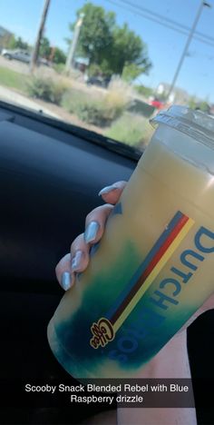 a person holding a drink in their hand with the sun shining through the car window