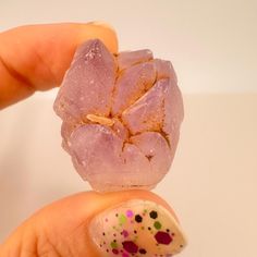 a hand holding a small piece of pink rock with sprinkles on it