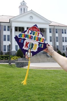 a person holding up a kite with writing on it in front of a large building