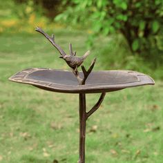 a metal bird bath sitting on top of a wooden table in the middle of a field